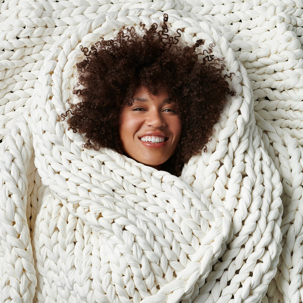Woman wrapped in a cloud white bearaby knitted blanket