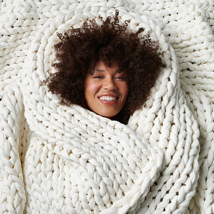 Woman wrapped in a cloud white bearaby knitted blanket