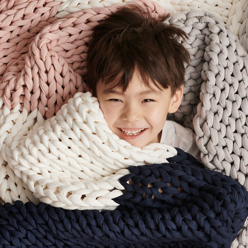 Child wrapped in a bearaby confetti knitted blanket