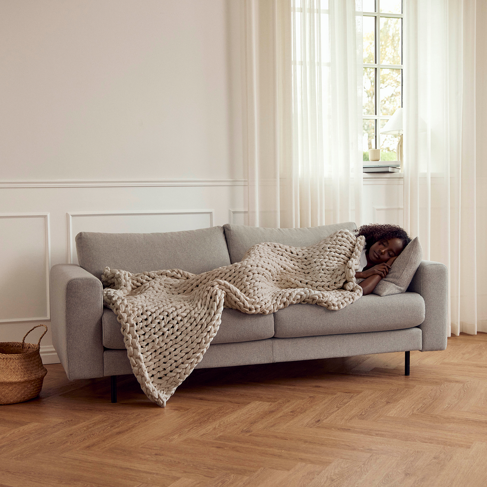 Person lying on a grey sofa with a bearaby driftwood ocean napper