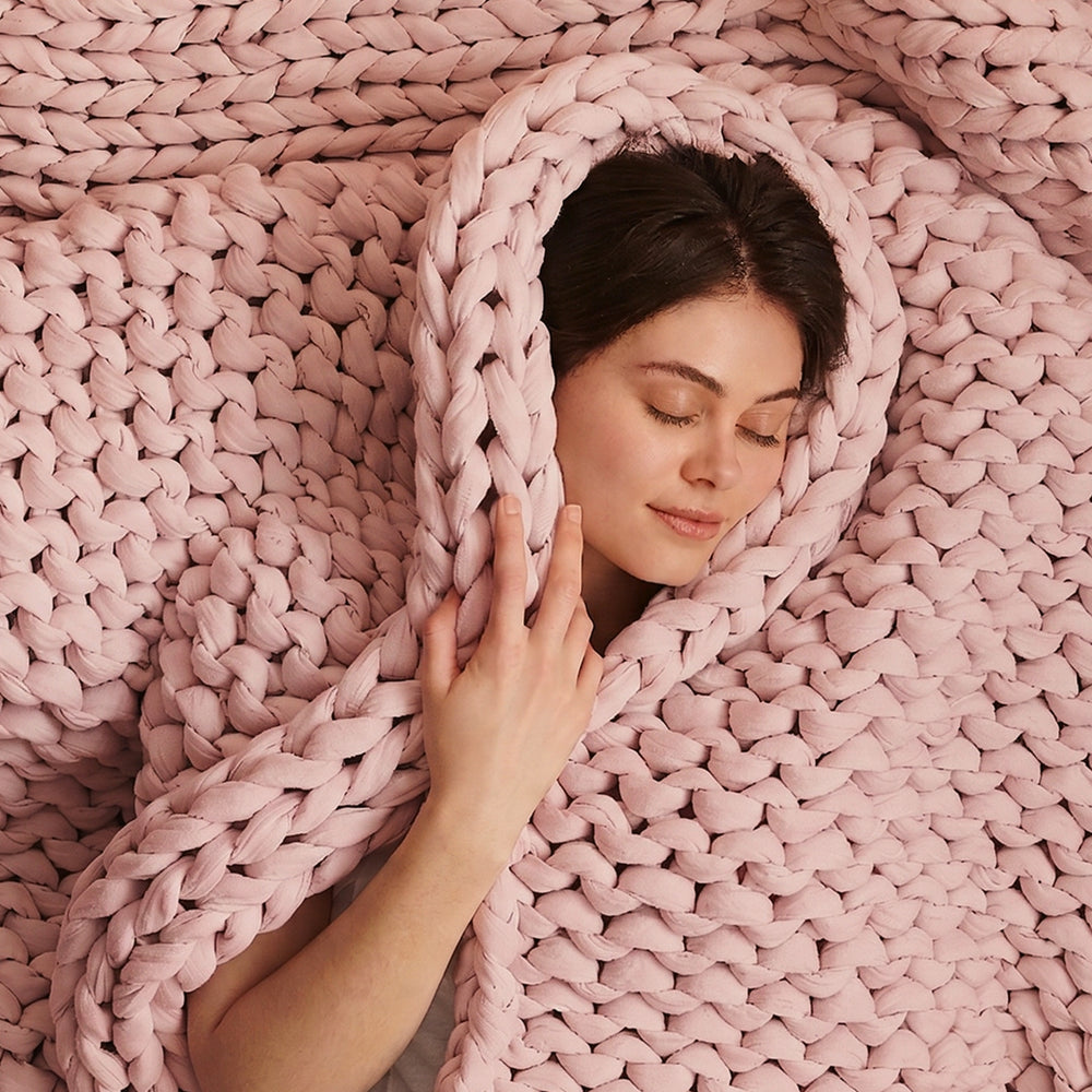Person wrapped in a pink bearaby knitted blanket