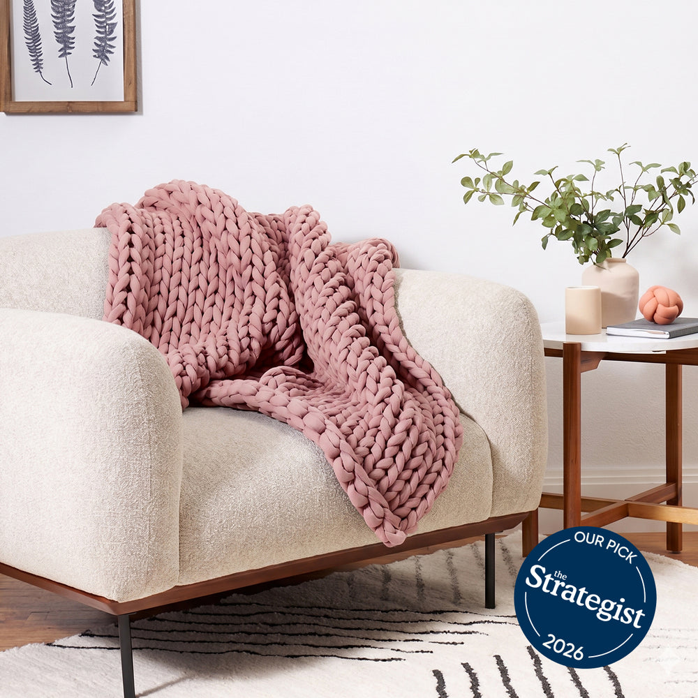 Pink bearaby knitted blanket on a beige sofa in a living room with a Strategist 2026 badge.