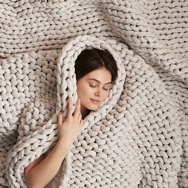 Lady about to fall asleep under woven weighted blanket