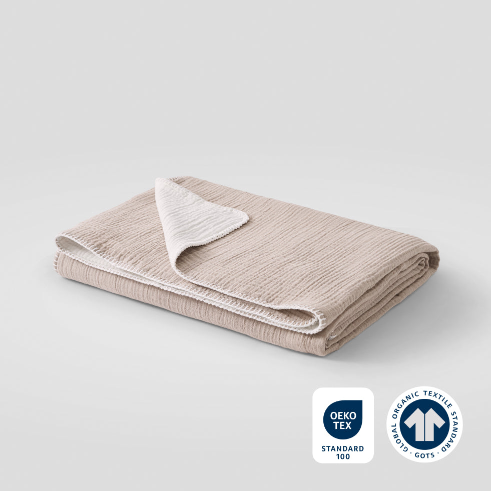 A softwood cotton muslin blanket with OEKO-TEX and GOTS certification badges in the lower right corner.