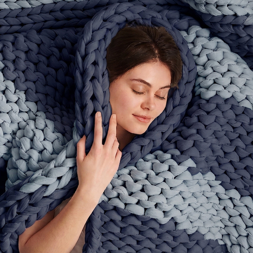 Woman wrapped in a sailboat blue knitted blanket