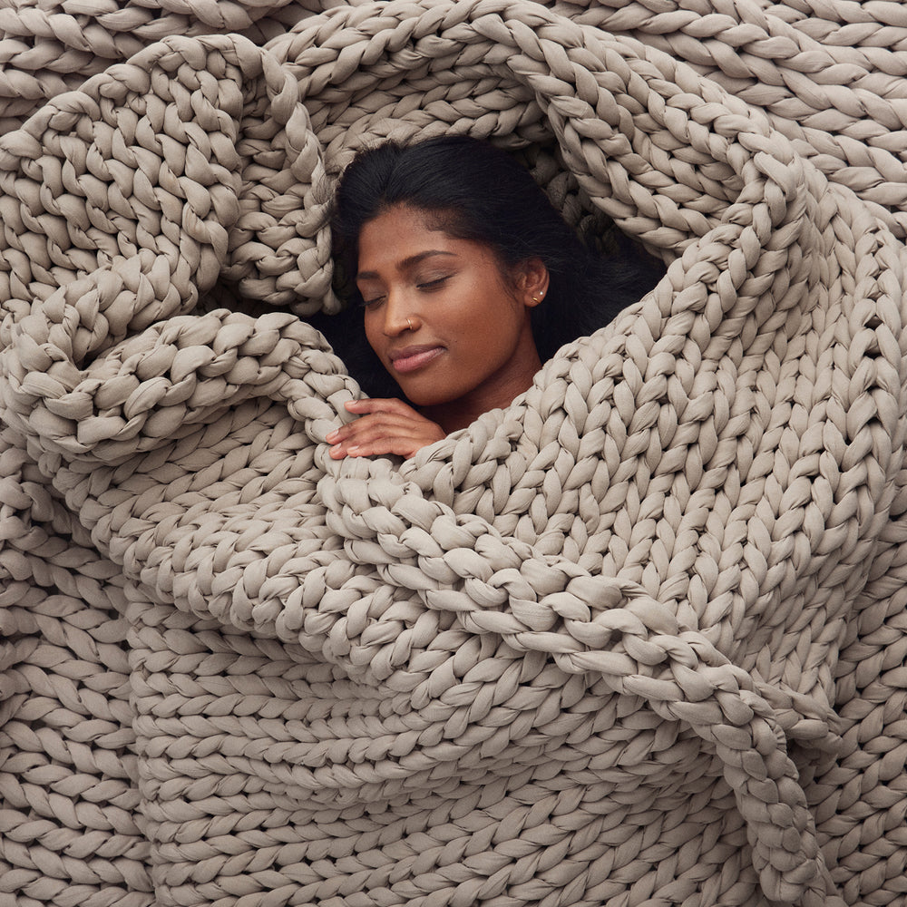 Woman wrapped in a softwood knitted beige blanket