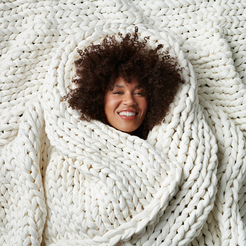 Happy woman about to fall asleep faster under the bearaby weighted blanket