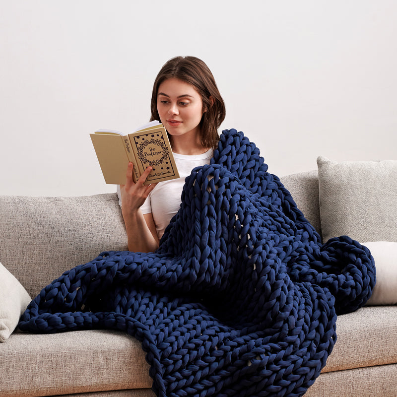 Lady calming down on the sofa with a warm hug from the braided weighted blanket